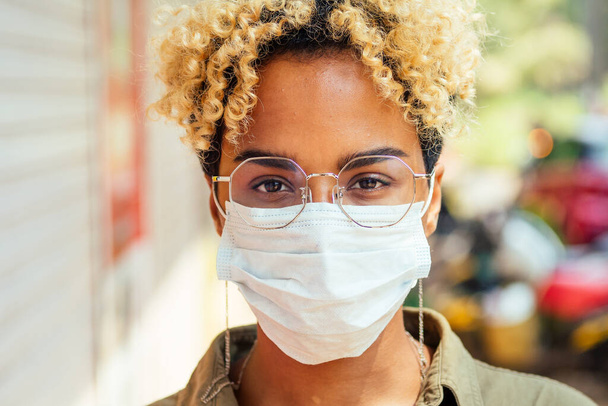 Afro woman in a protective mask stands on the street. coronavirus concept - Φωτογραφία, εικόνα