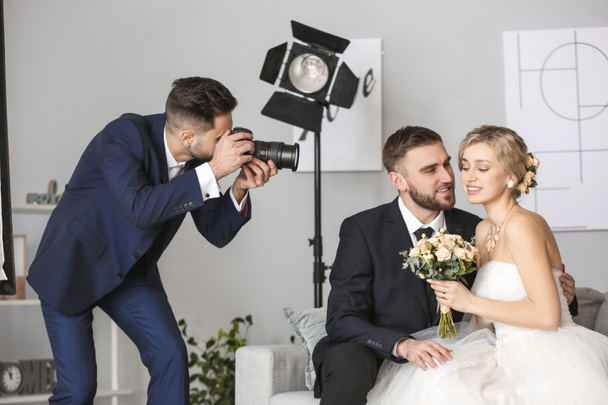 Фотограф работает с молодой свадебной парой в студии
 - Фото, изображение