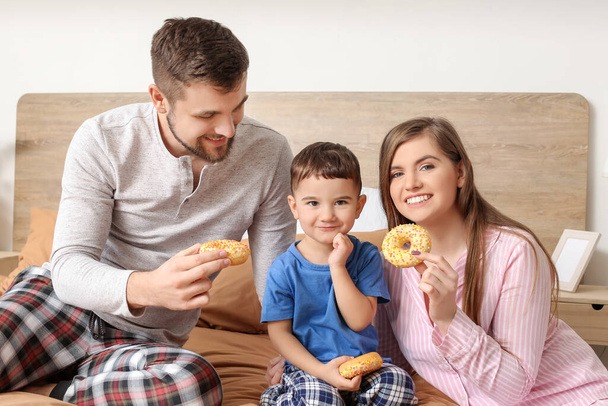 Happy family eating donuts in bedroom - Photo, Image