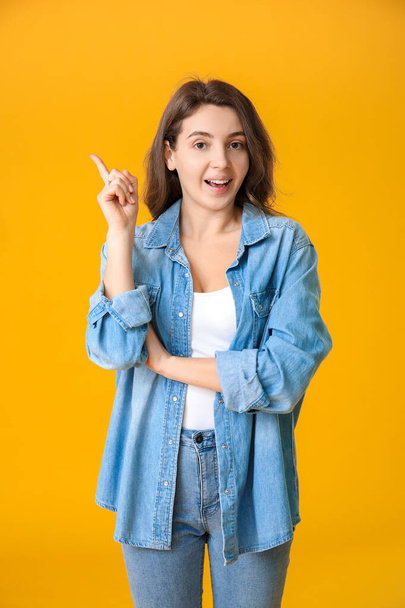 Beautiful young girl with raised index finger on color background - Φωτογραφία, εικόνα