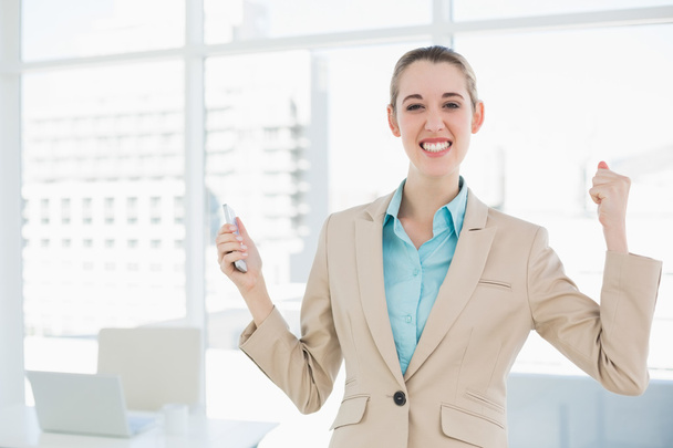 Attractive cheerful businesswoman holding her smartphone - Photo, Image