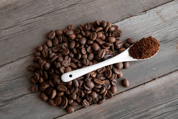  white ceramic spoon with ground coffee on a wooden background Fried Arabica grains. - Φωτογραφία, εικόνα