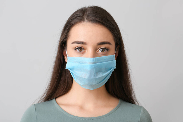 Mujer joven con máscara médica contra fondo gris
 - Foto, imagen
