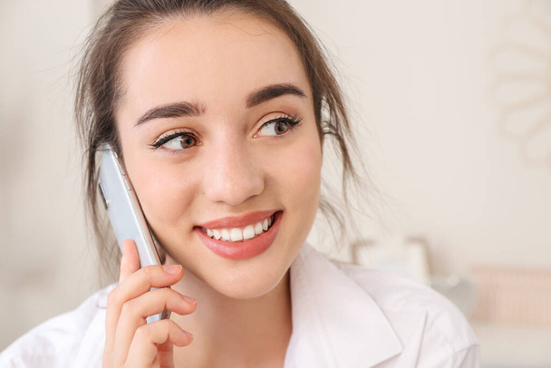 Gyönyörű fiatal nő beszél telefonon, miközben otthon dolgozik - Fotó, kép