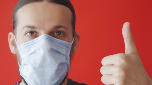 Πορτρέτο ενός άρρωστου άντρα που φοράει ιατρική μάσκα σε κόκκινο φόντο. Ιός του κερατοειδούς. Προστατέψτε την υγεία σας - Πλάνα, βίντεο