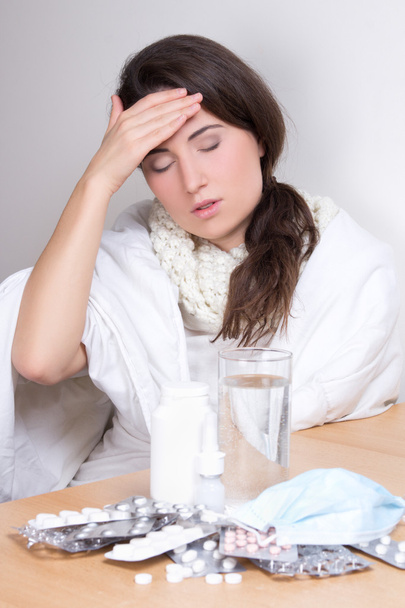 mujer joven con dolor de cabeza y pastillas en la mesa - Foto, imagen