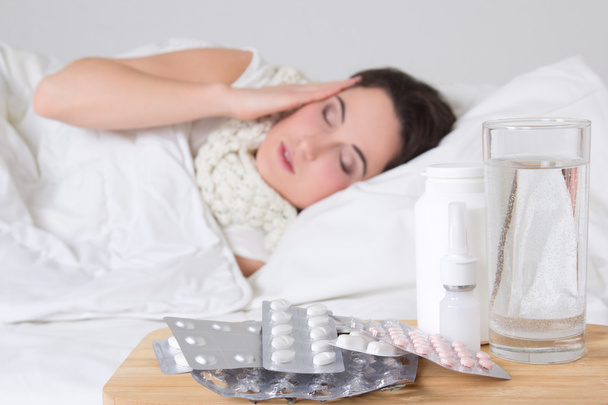 άρρωστη γυναίκα στο κρεβάτι και χάπια στο τραπέζι - Φωτογραφία, εικόνα