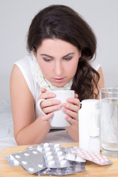 donna bruna, bere tè e pillole sul tavolo - Foto, immagini