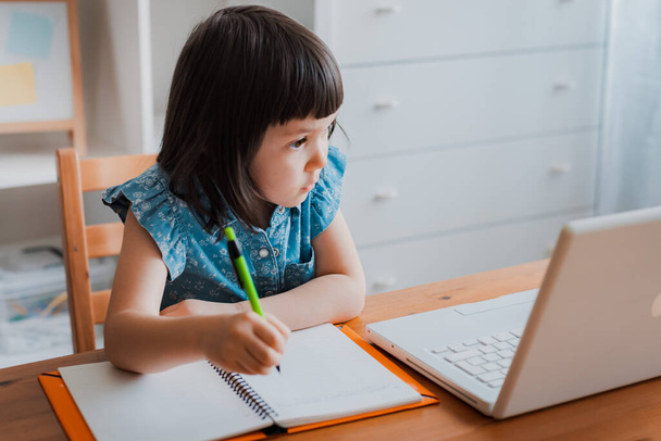 Vzdálenost učení on-line vzdělávání. Děvčátko doma a dělá domácí úkoly. Domácí distanční vzdělávání. - Fotografie, Obrázek