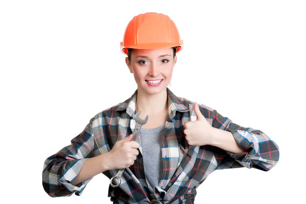 Beautiful girl in a building helmet holding a wrench - Zdjęcie, obraz