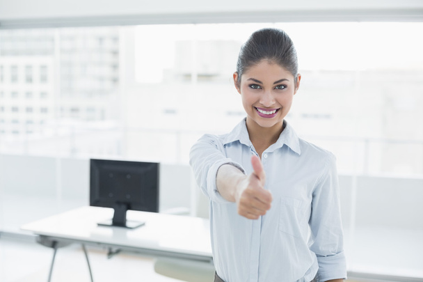 Smiling businesswoman gesturing thumbs up at office - Фото, изображение
