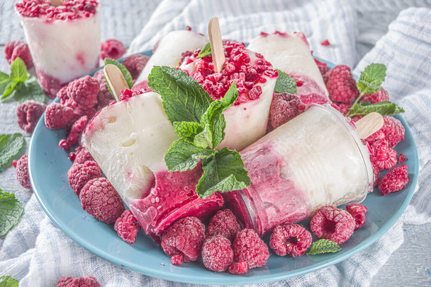 Słodka i smaczna dieta letni deser. Domowej roboty jogurt malinowy popsicle ze świeżymi malinami i miętą. Zdrowy przepis na lody. Drewniany biały tło kopia przestrzeń - Zdjęcie, obraz