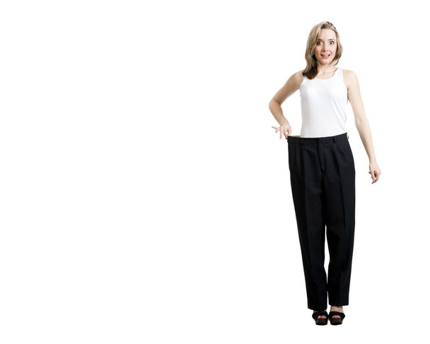 Beautiful sexy blonde girl in black trousers and a shirt, showing her lost weight on a white background isolation - Fotoğraf, Görsel