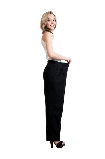 Beautiful sexy blonde girl in black trousers and a shirt, showing her lost weight on a white background isolation - Zdjęcie, obraz