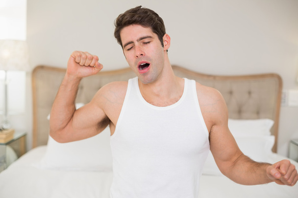 Jeune homme se réveillant au lit et étirant les bras
 - Photo, image