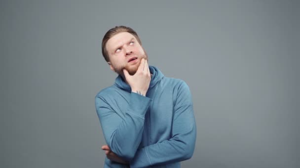 Video of thoughtful blond man in blue sweatshirt - Кадры, видео