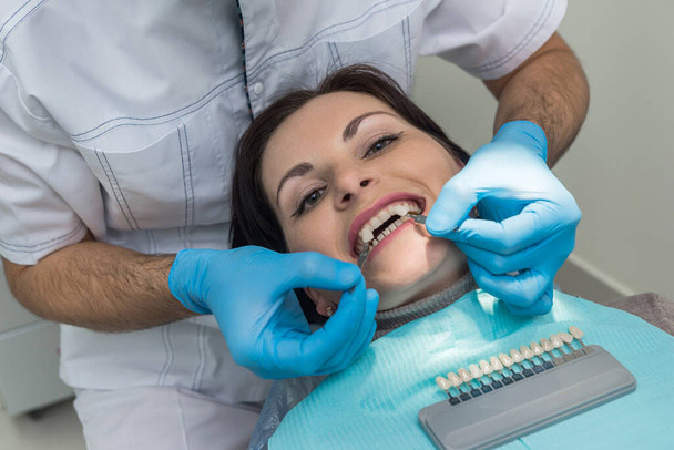 Dentist comparing patient teeth with crown sampler - Fotó, kép