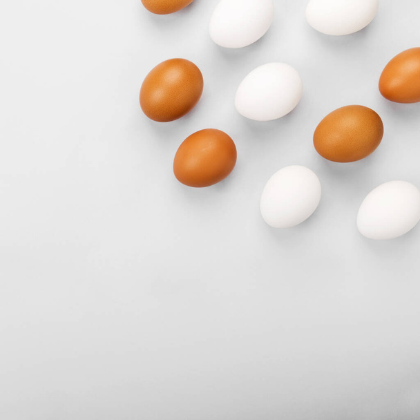 Group of raw eggs white and brown. Concept of diversity, isolation, racism, inequality. On gray background. Top view, copy space - Photo, Image