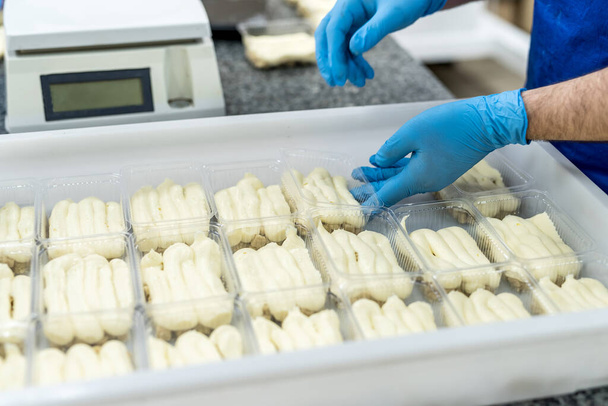 Mãos de confetor com sobremesas em embalagem de plástico colocando-o para congelamento. Fabricação industrial de alimentos
 - Foto, Imagem