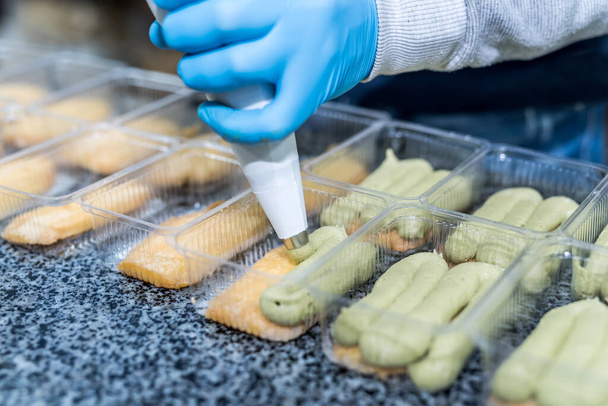 Dessert aux pistaches coloré et délicieux dans un emballage en plastique sur la table en usine. Industrie alimentaire
 - Photo, image