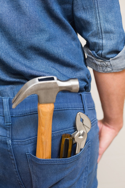 Several tools in a man's rear denim pocket - 写真・画像