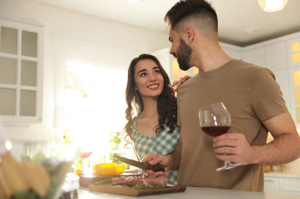 Lovely young couple cooking meat together in kitchen - Foto, Bild