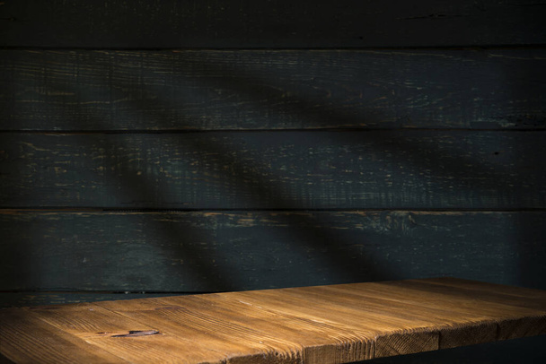 Old wood table with blurred concrete block wall in dark room background. - Photo, Image