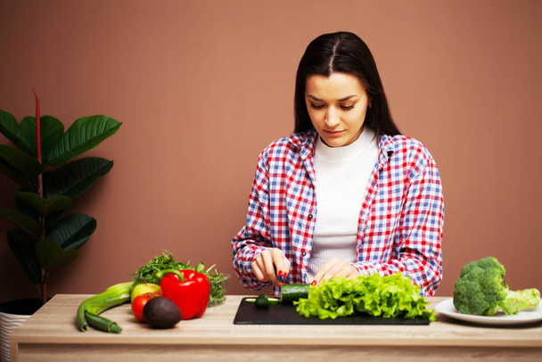 Mujer bonita preparando una ensalada dietética de verduras frescas en casa en la cocina
 - Foto, imagen