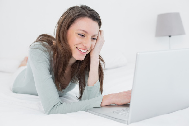 Cheerful relaxed casual woman with laptop in bed - Фото, изображение