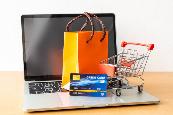 hitelkártya és kosár szupermarket és narancssárga papírzacskó fa asztalon. vásárlási koncepció - Fotó, kép