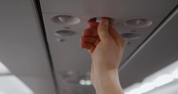 Mužská ruka zapne vzduch v kabině letadla. Koncept cestovního ruchu a cestování - Záběry, video