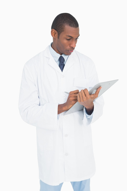 Serious male doctor writing on clipboard - Photo, Image