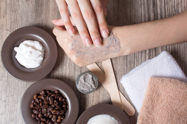 Een vrouw brengt een natuurlijke koffie scrub aan op de huid. Zelfgemaakte scrub gemaakt van suiker, zout, room en koffie. Schoonheid, Spa, huidverzorging, aromatherapie. Vochtinbrengend, schilferend, exfoliërend - Foto, afbeelding