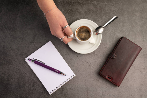 Koffiebeker met telefoon en notebook op een donkere achtergrond - Foto, afbeelding