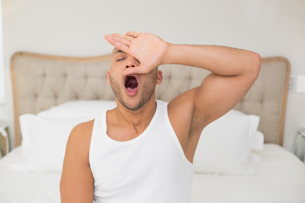 Young man yawning in bed - Fotó, kép