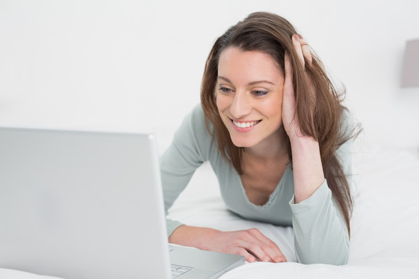 Relaxed casual smiling woman using laptop in bed - Fotoğraf, Görsel