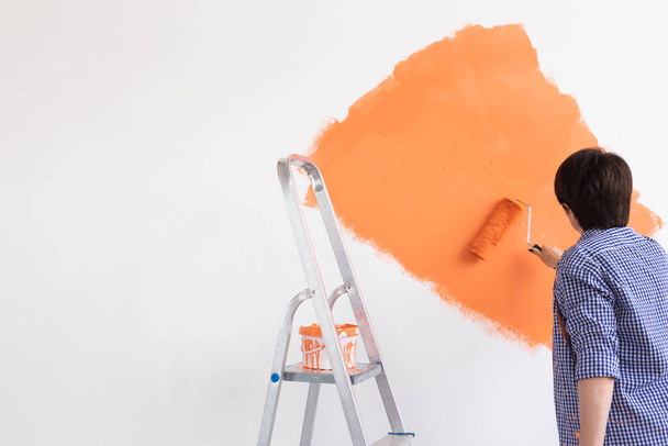 Renovatie, herinrichting en reparatie concept - vrouw van middelbare leeftijd schilderen muur in nieuw huis. - Foto, afbeelding