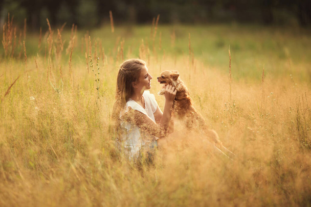 young girl is playing with dog in field - Foto, immagini