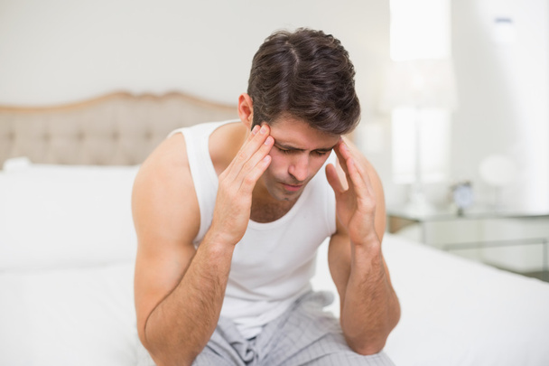 Young man suffering from headache in bed - Foto, Imagen
