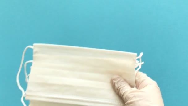 Doctor's hand in medical glove holds several typical disposable surgical masks white color to cover the mouth and nose. Concept of anti-virus protection Coronavirus, COVID-19 and other dangerous viruses. 4K Resolution - Video