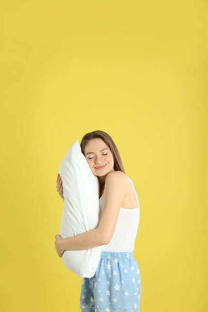 Young woman with pillow on yellow background - Photo, image
