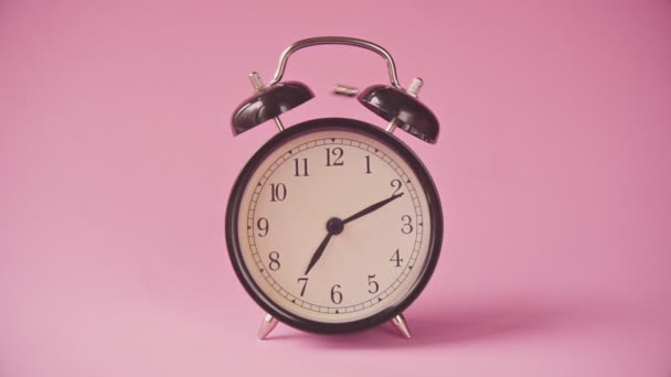 Black alarm clock on a pink background.  - Footage, Video