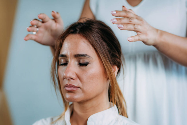 Terapeuta de Shamballa sosteniendo las manos sobre la cabeza de la clienta. Tratamiento con Shambhala
 - Foto, Imagen