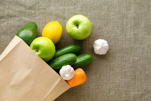 Grocery paper bag with vegetables and fruits on textile background - Valokuva, kuva