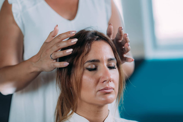 Terapeuta de Shamballa sosteniendo las manos sobre la cabeza de la clienta. Tratamiento con Shambhala
 - Foto, imagen