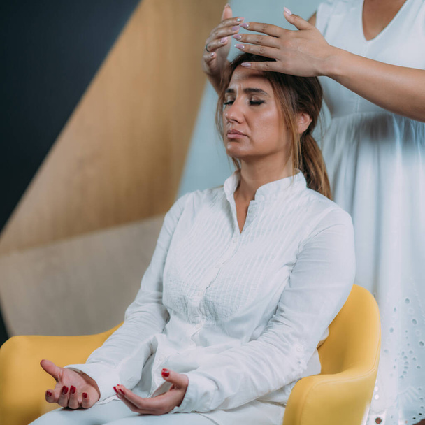 Terapeuta de Shamballa sosteniendo las manos sobre la cabeza de la clienta. Tratamiento con Shambhala
 - Foto, Imagen