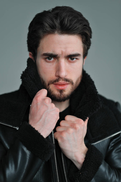 A large portrait of a stylish young man with a beard and dark hair in a black leather jacket - Photo, image