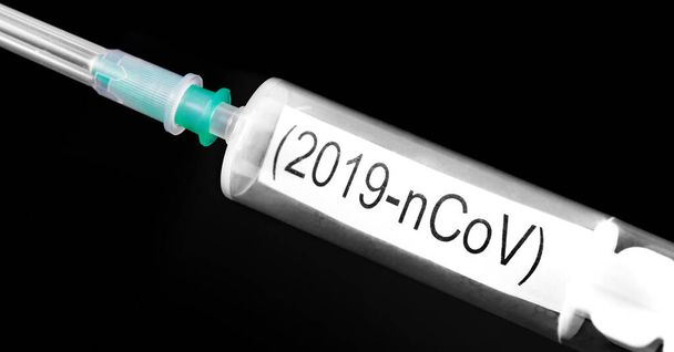 Romanzo coronavirus (2019-nCoV). Siringa con testo (2019-nCoV) sullo sfondo nero primo piano - Foto, immagini