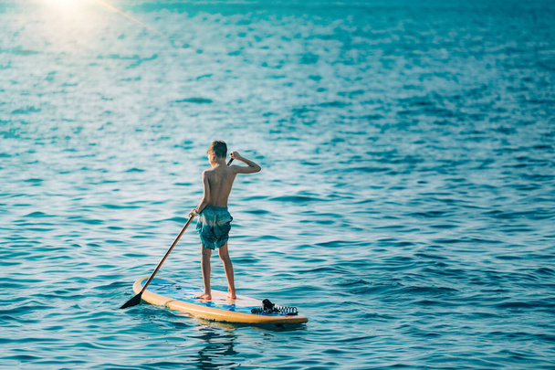 Boy having fun with Stand Up Paddling Board  - Foto, Imagen