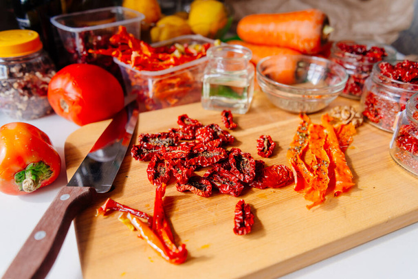 Sun-dried tomatoes and dried carrots with olive oil and Provencal herbs. The process of making dried tomatoes. Ingredients for Vegetable Chips top view - Zdjęcie, obraz